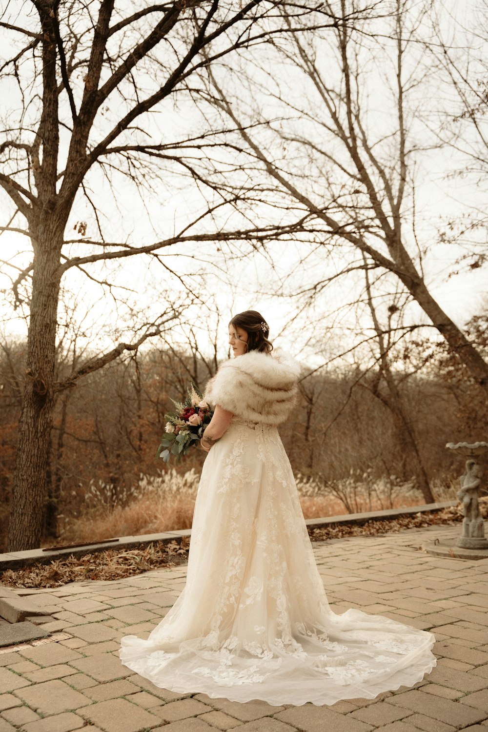 una donna in un abito da sposa in piedi di fronte a un albero