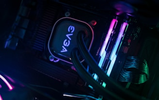 A close-up view of a computer's internal components, highlighting a water cooling block branded with EVGA along with RGB lighting on RAM sticks. The cables are neatly arranged, and the lighting casts a soft glow.