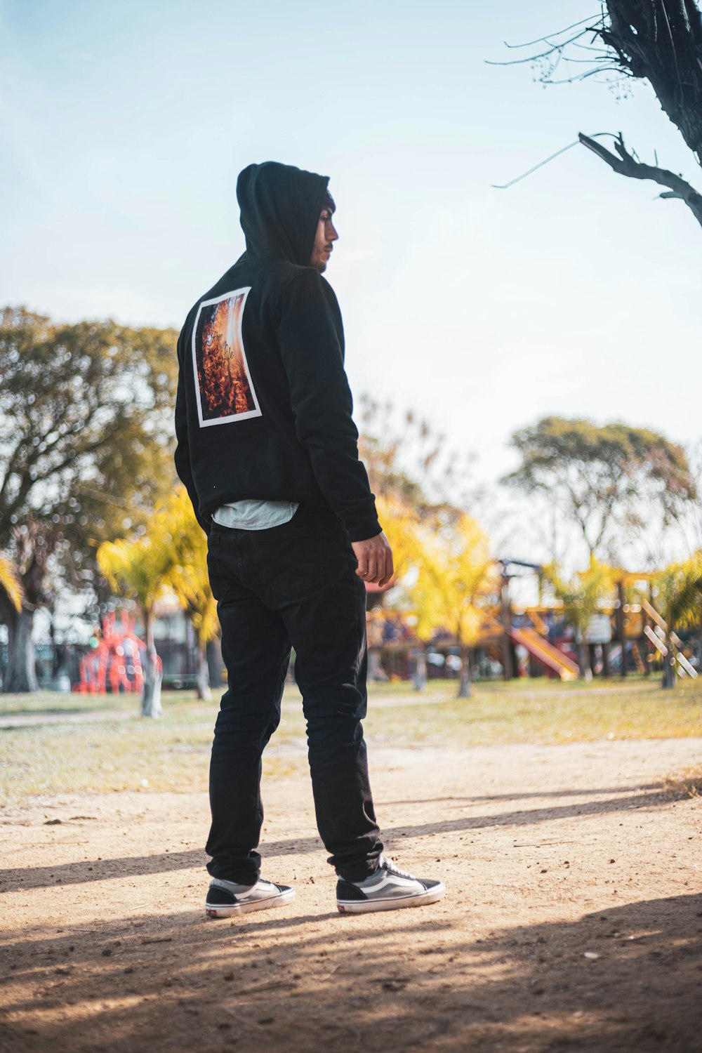 a man in a black hoodie standing in a park