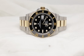 a black and gold rolex watch on a white background