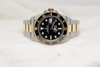 a black and gold rolex watch on a white background