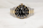 a black and gold rolex watch on a white background