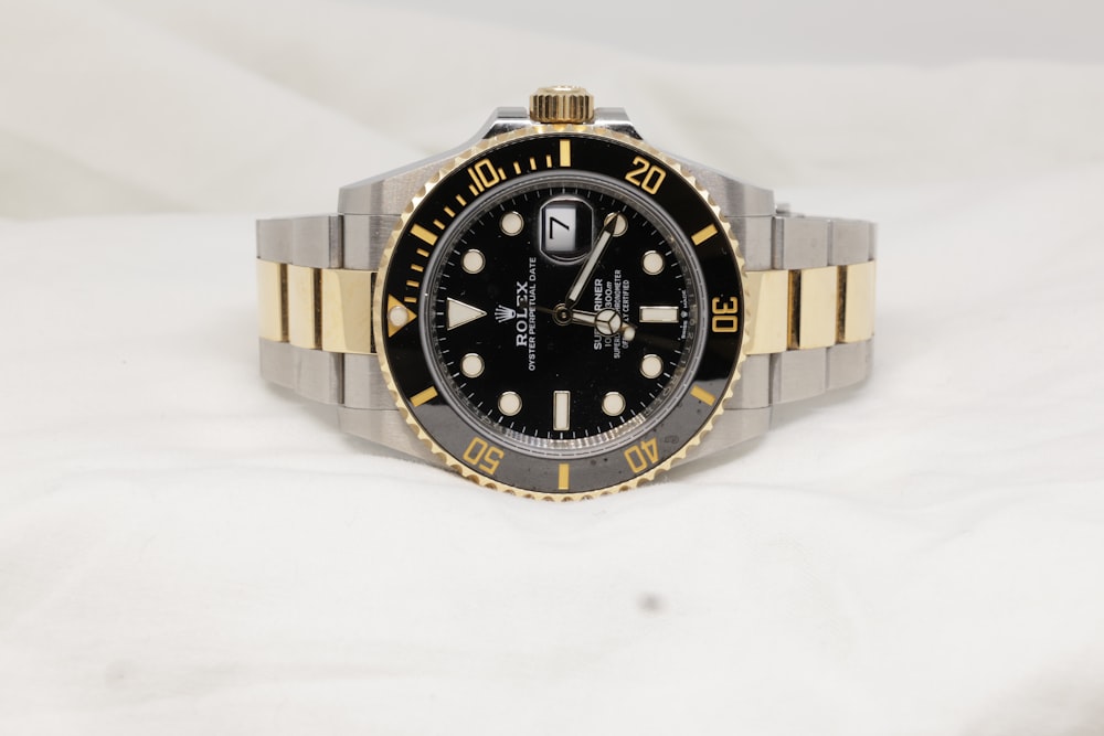 a black and gold rolex watch on a white background