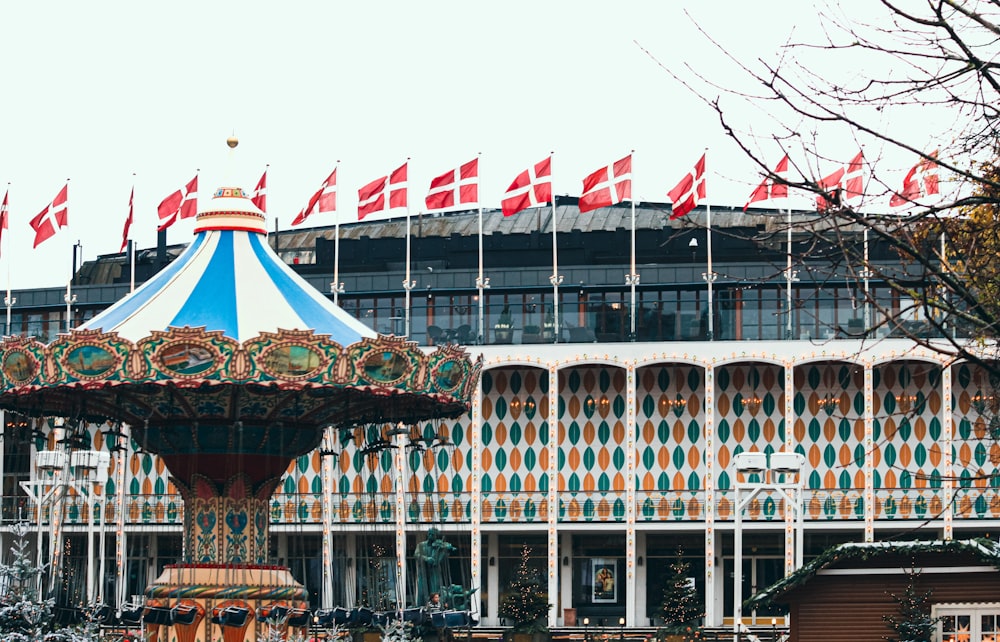a carousel in front of a building with flags on it