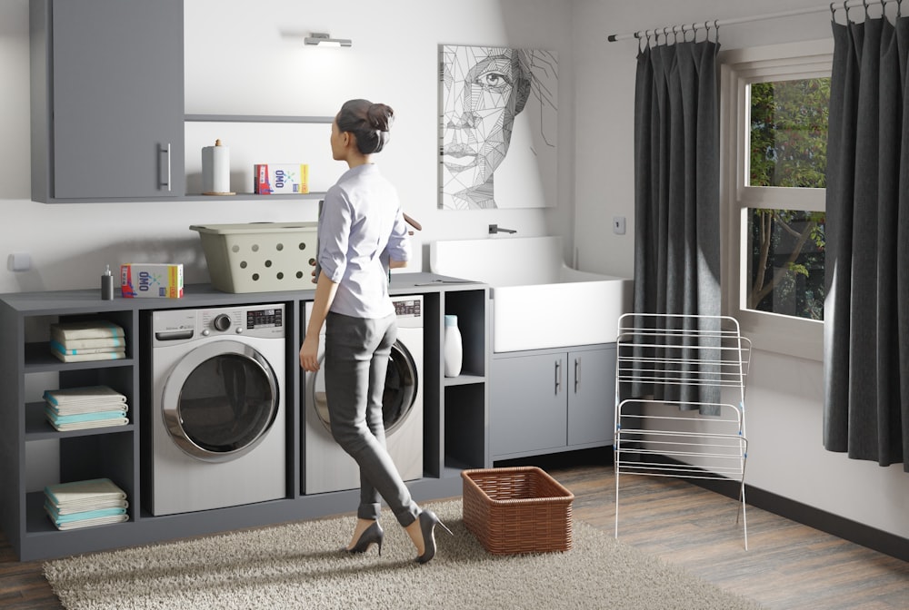 a woman standing in a laundry room next to a washer and dryer