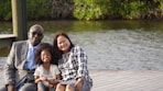 a man, woman and child sitting on a dock