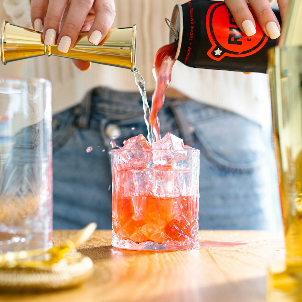 a person pouring a drink into a glass