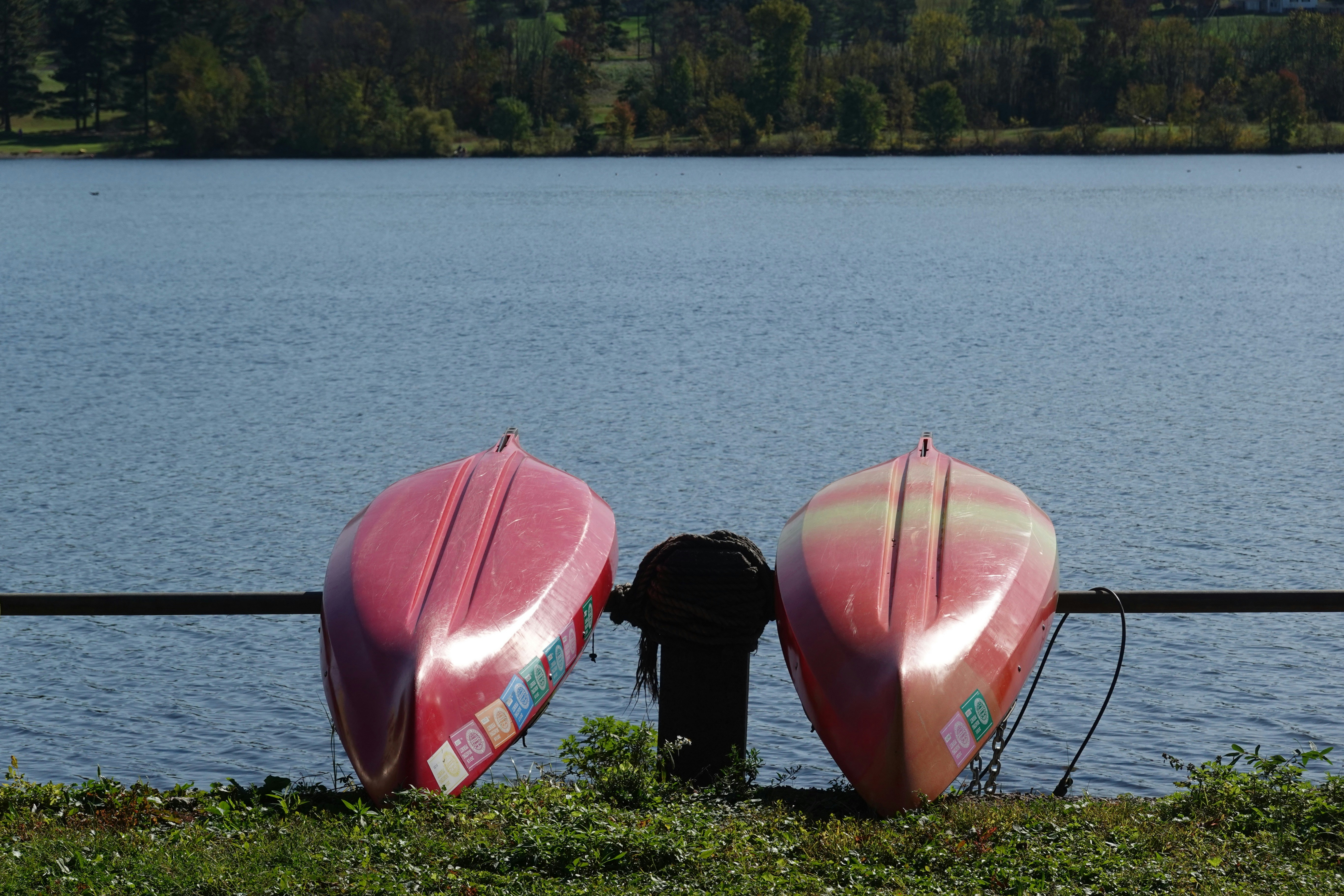 two red and white canoes sitting on the shore of a lake