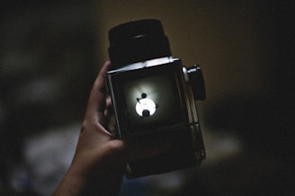 a person holding a camera with an apple logo on it