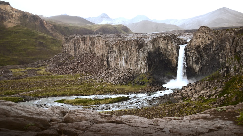 a large waterfall in the middle of a mountain range