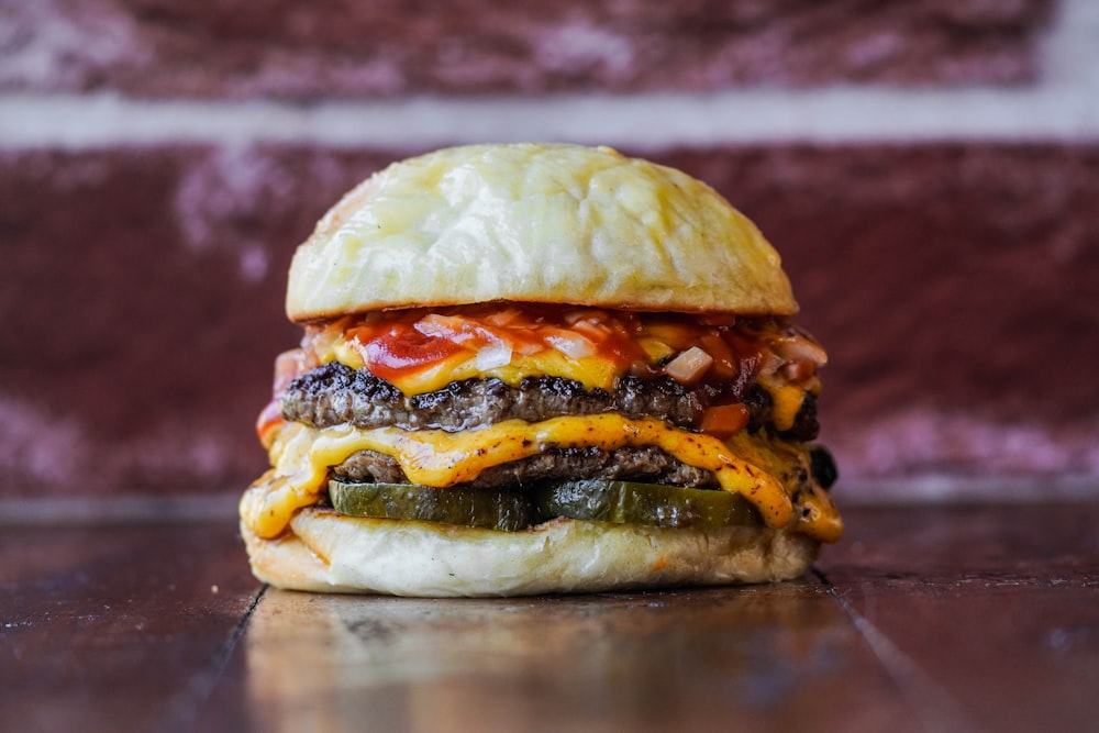 una hamburguesa con queso en un bollo con un pepinillo a un lado