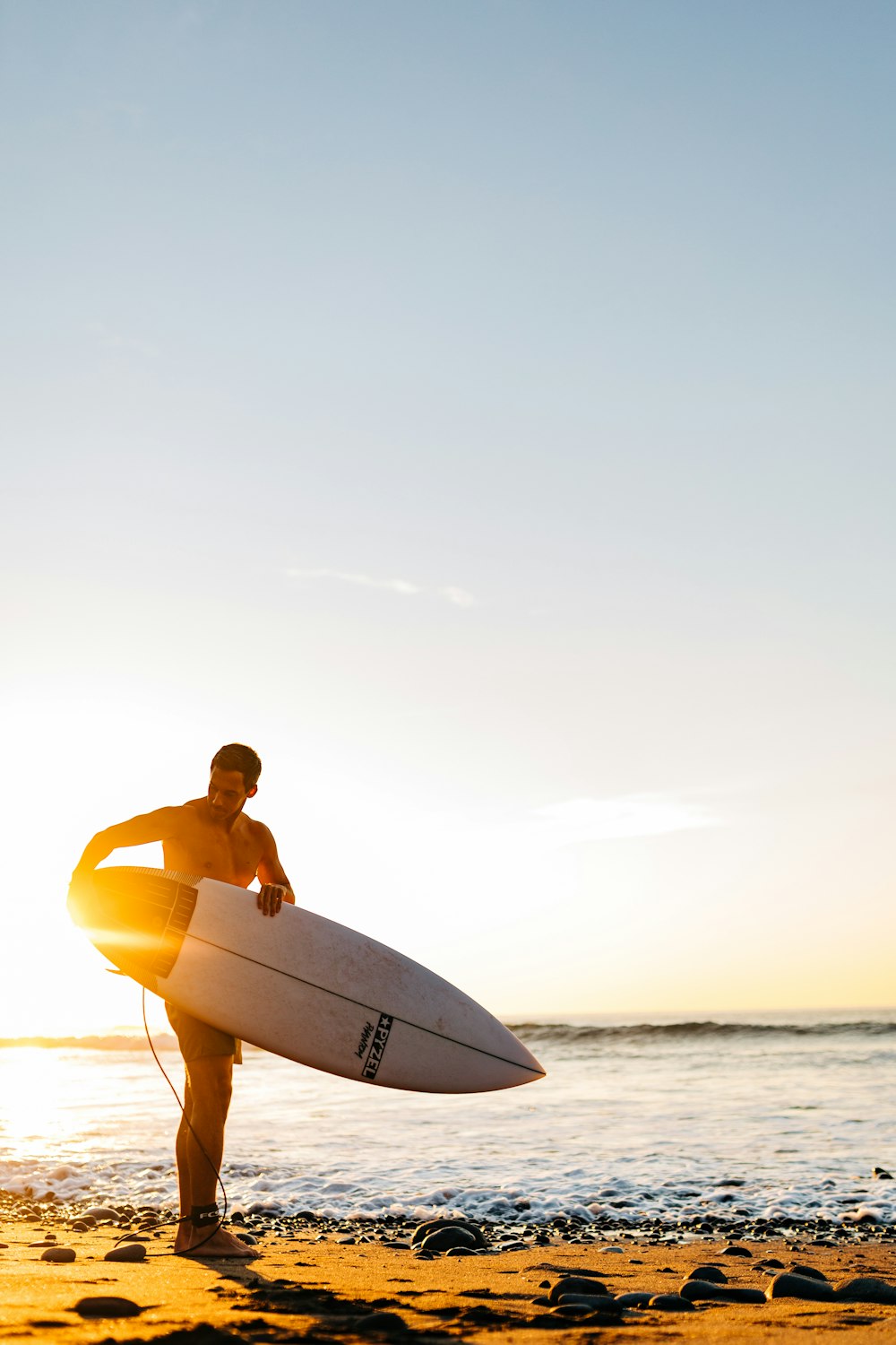 a man standing on a beach holding a surfboard