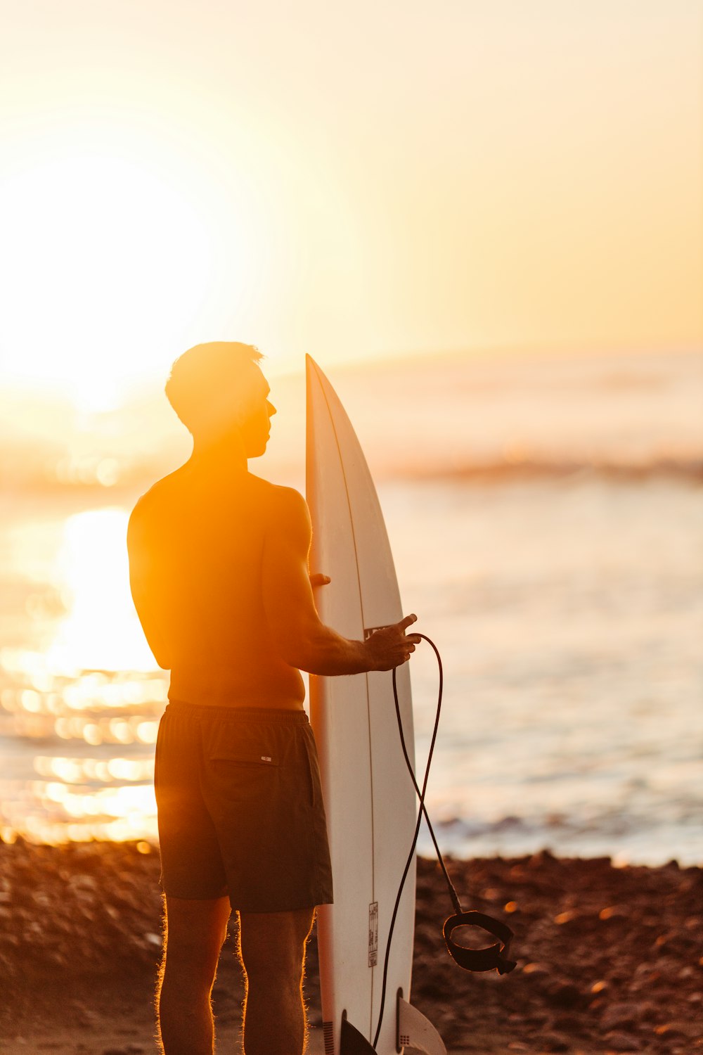 Un homme debout sur une plage tenant une planche de surf