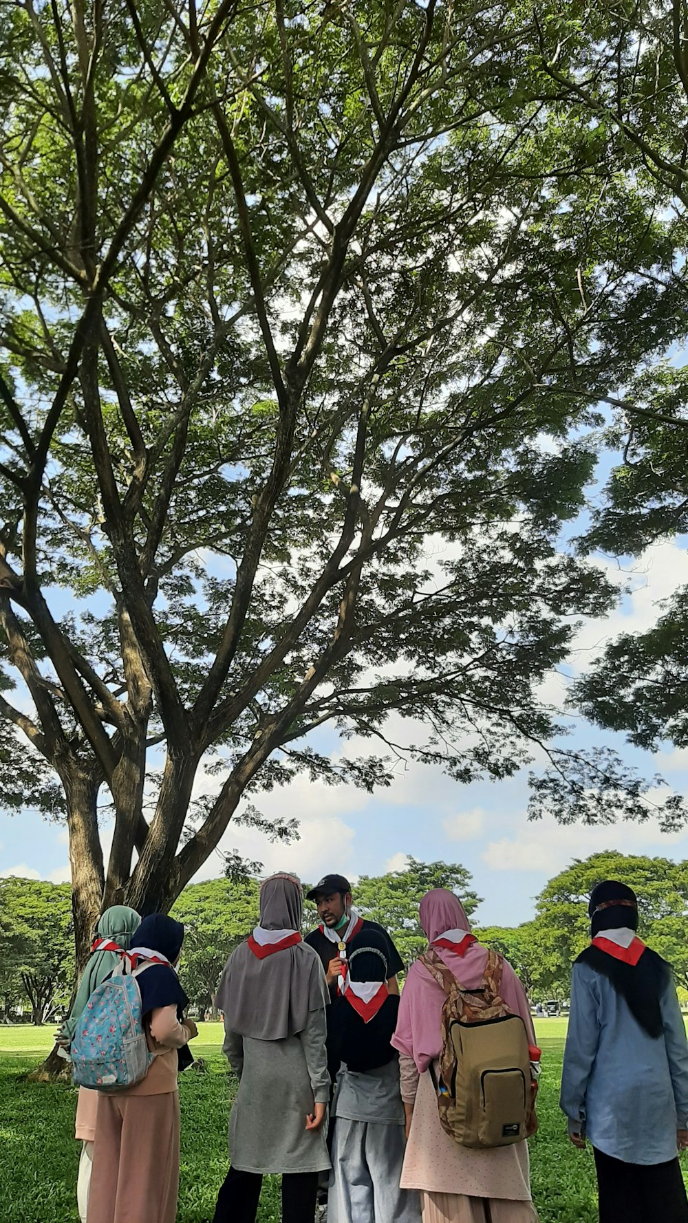 a group of people standing in front of a tree