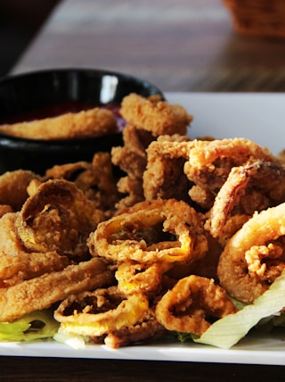 a white plate topped with onion rings and a bowl of dipping sauce