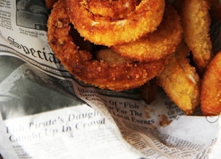 a pile of fried onion rings sitting on top of a newspaper