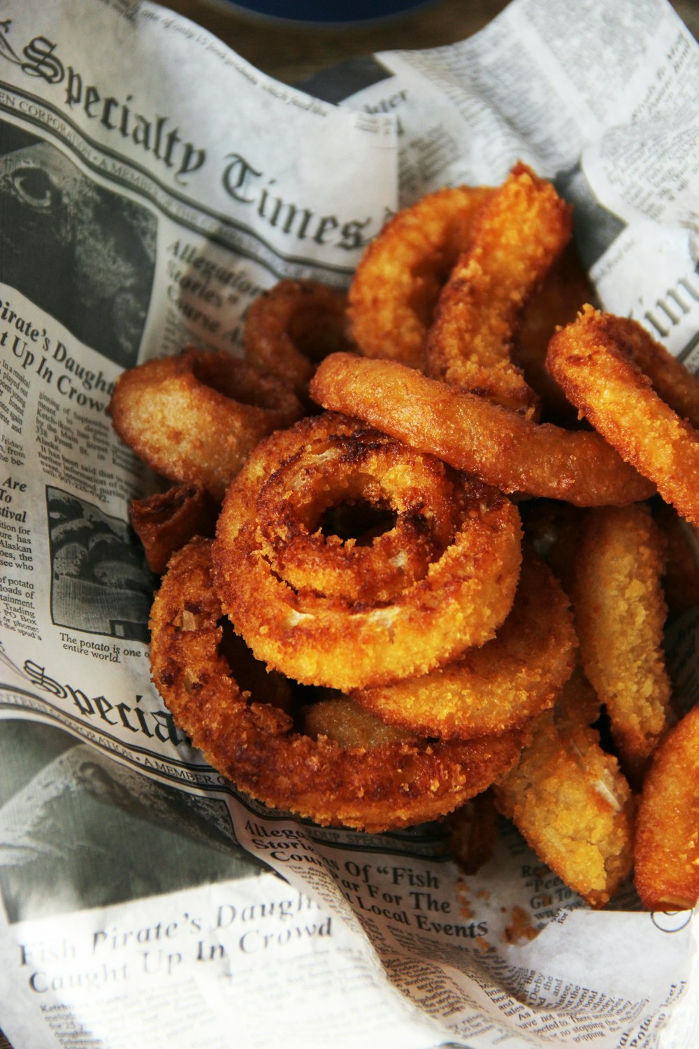 a pile of fried onion rings sitting on top of a newspaper