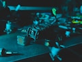 A close-up view of a drone placed on a table, featuring visible propellers and camera. The environment appears dimly lit, creating a moody atmosphere.