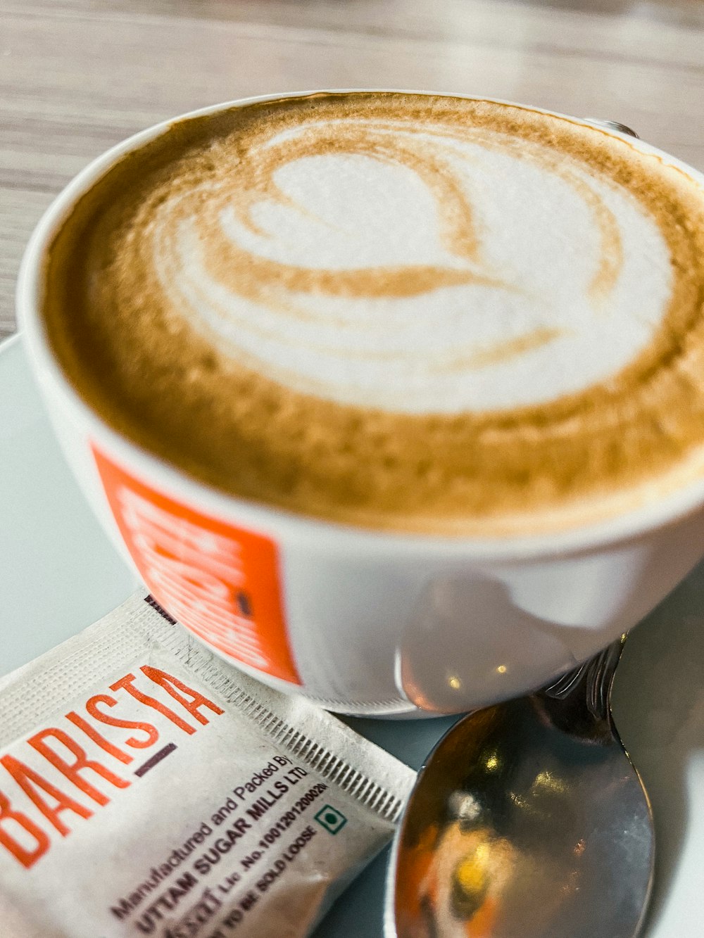 a cup of cappuccino with a spoon next to it