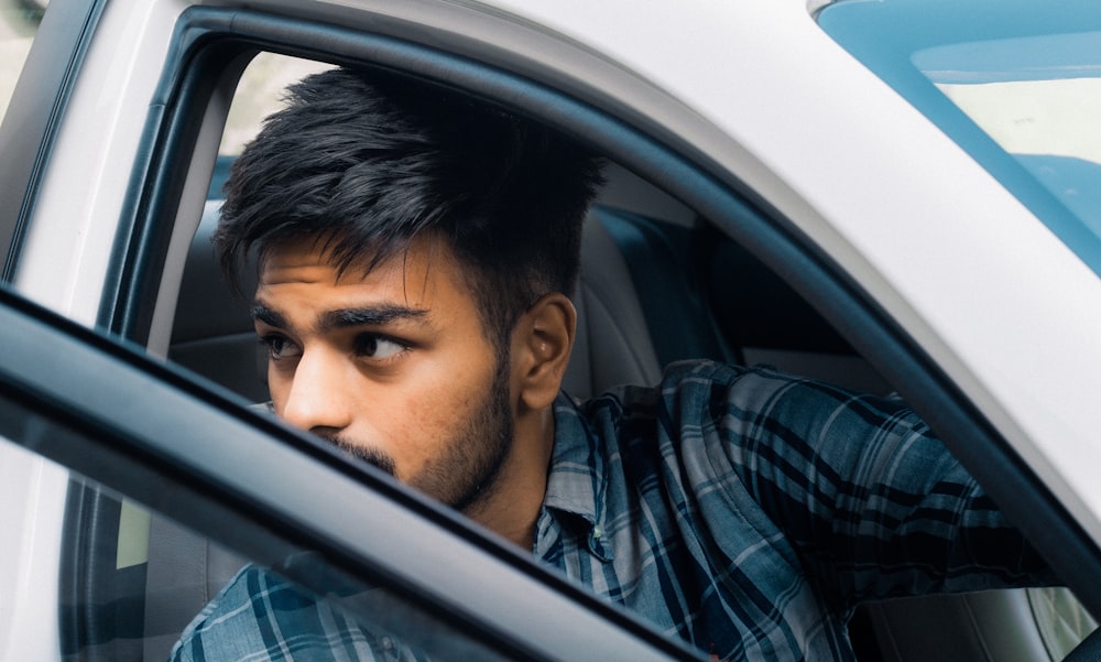 a man sitting in a car looking out the window