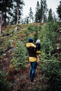a woman carrying a child through a forest