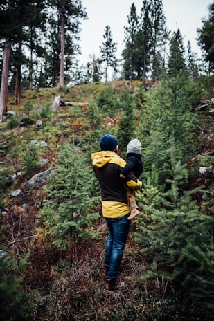 a woman carrying a child through a forest