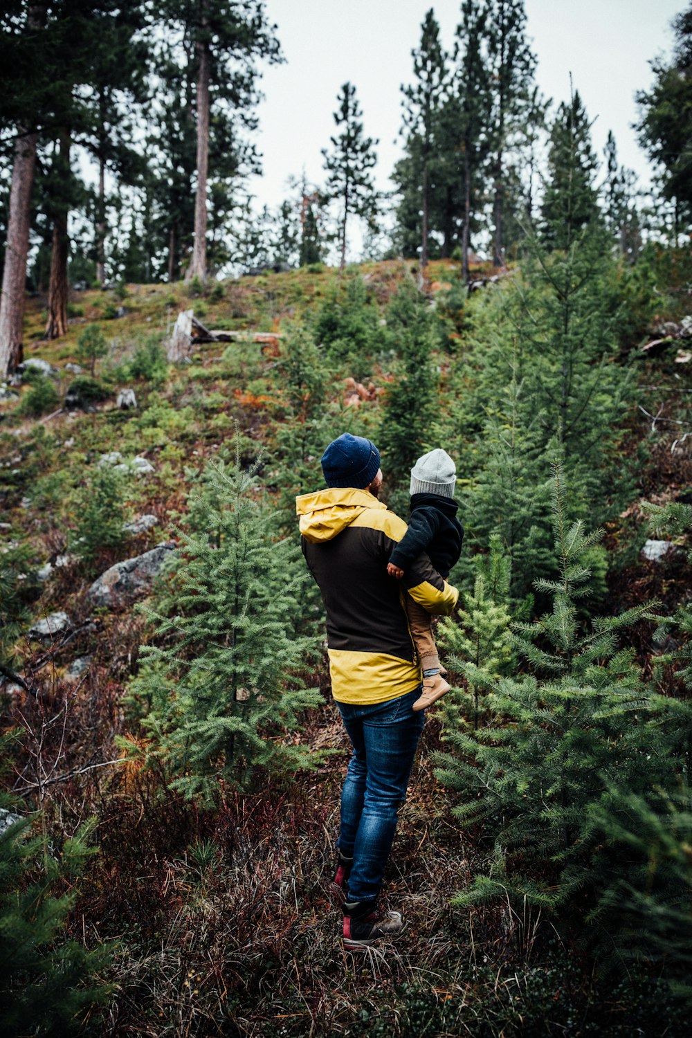 a woman carrying a child through a forest