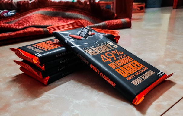 Stacks of chocolate bars wrapped in elegant packaging with the js sweets logo visible.