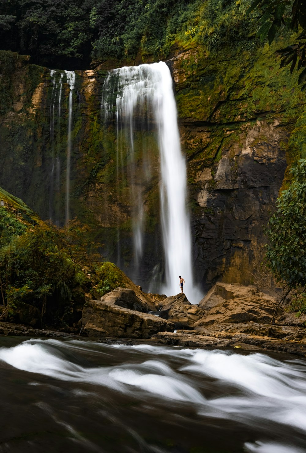 a man standing in front of a waterfall