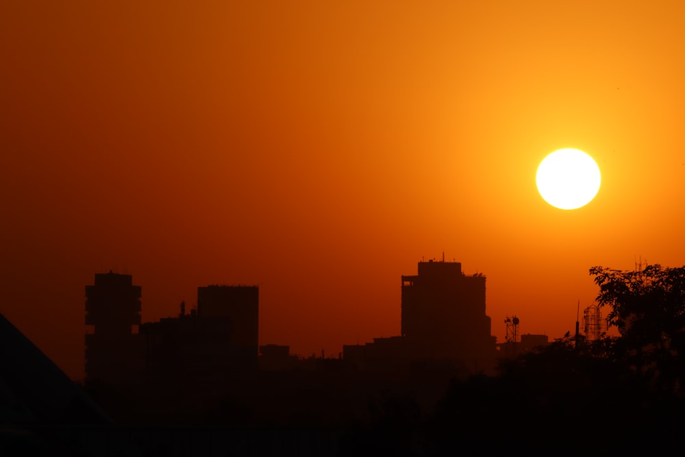 the sun is setting over a city with tall buildings