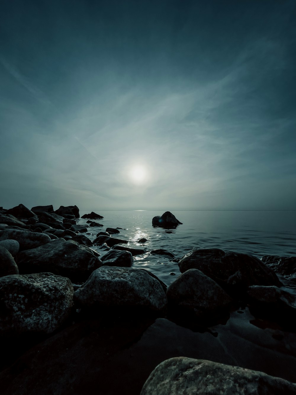 a black and white photo of the ocean and rocks