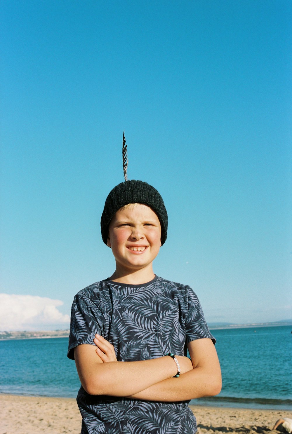 a young boy standing on top of a sandy beach