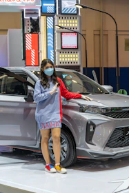 a woman wearing a face mask standing next to a car