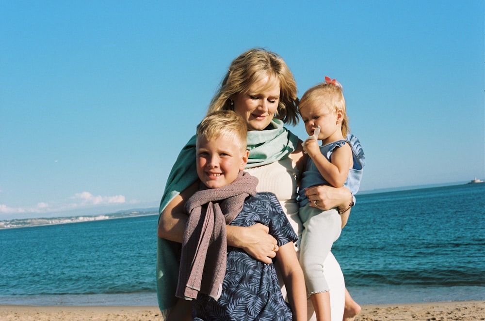 a woman holding two children on a beach