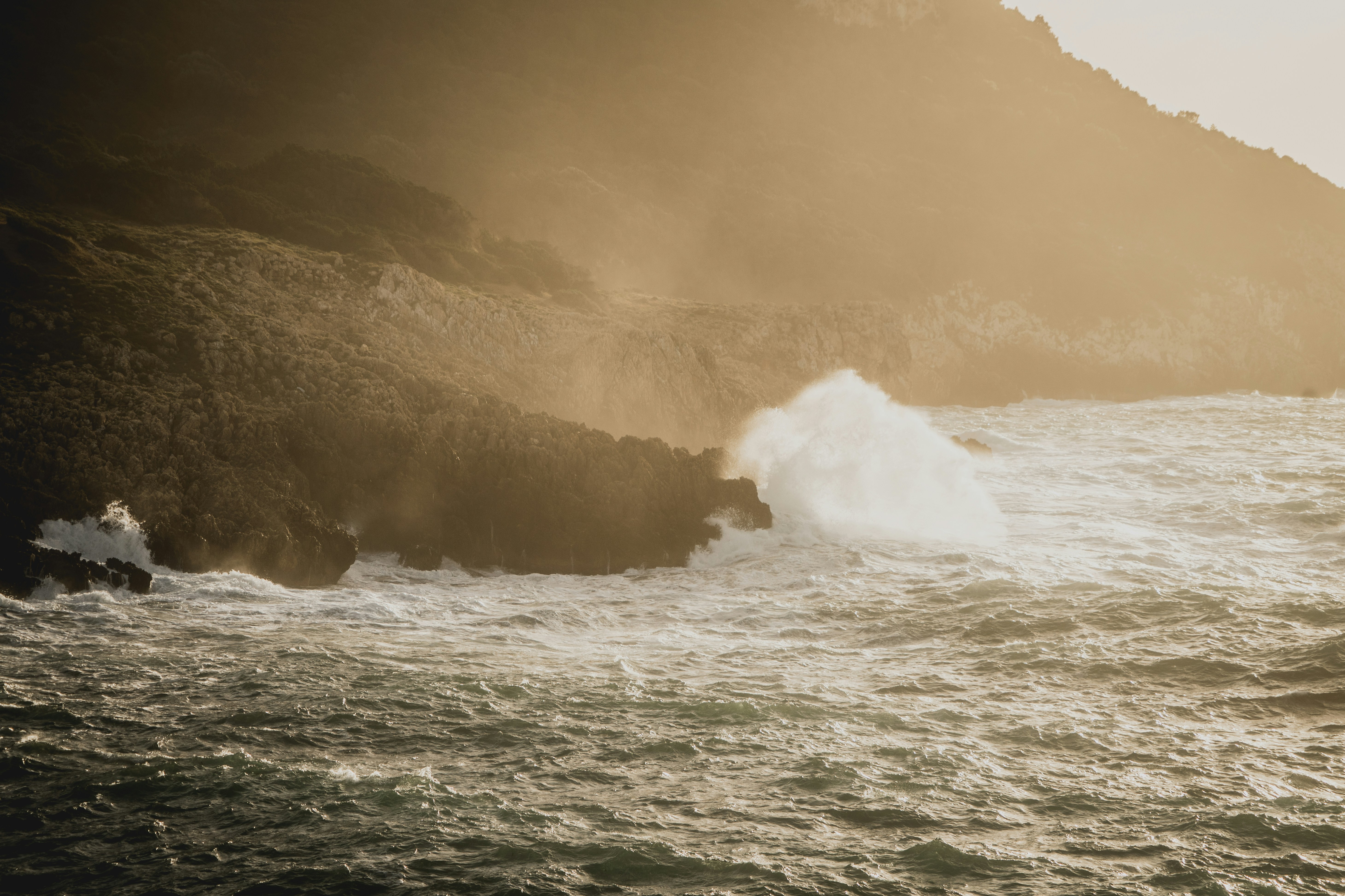 a large wave crashing into a rocky shore