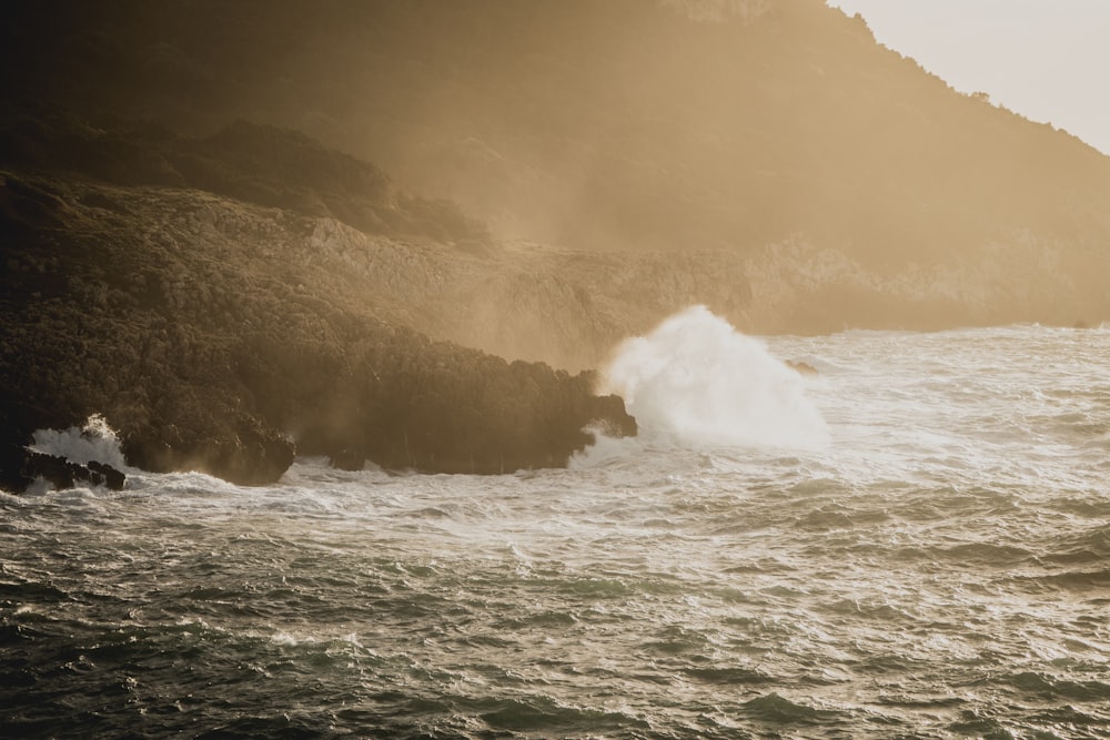 a large wave crashing into a rocky shore