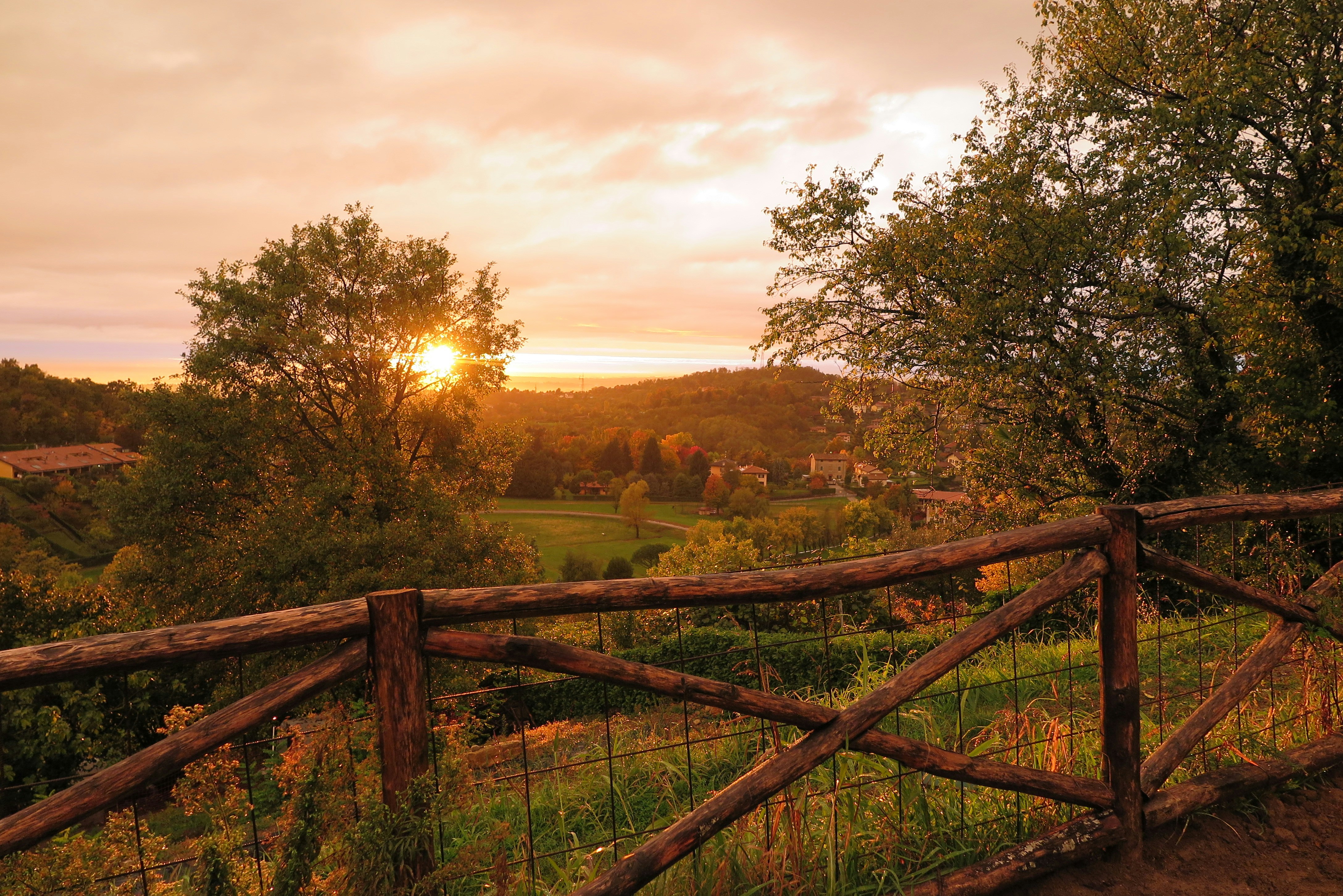 the sun is setting behind a wooden fence