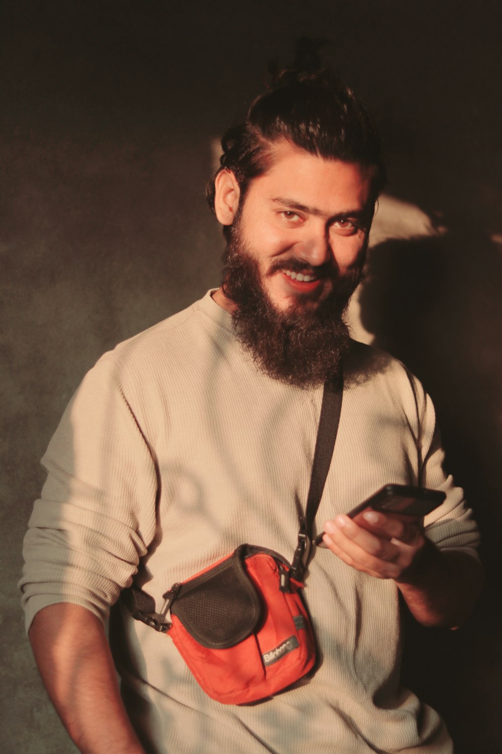 a man with a beard holding a cell phone