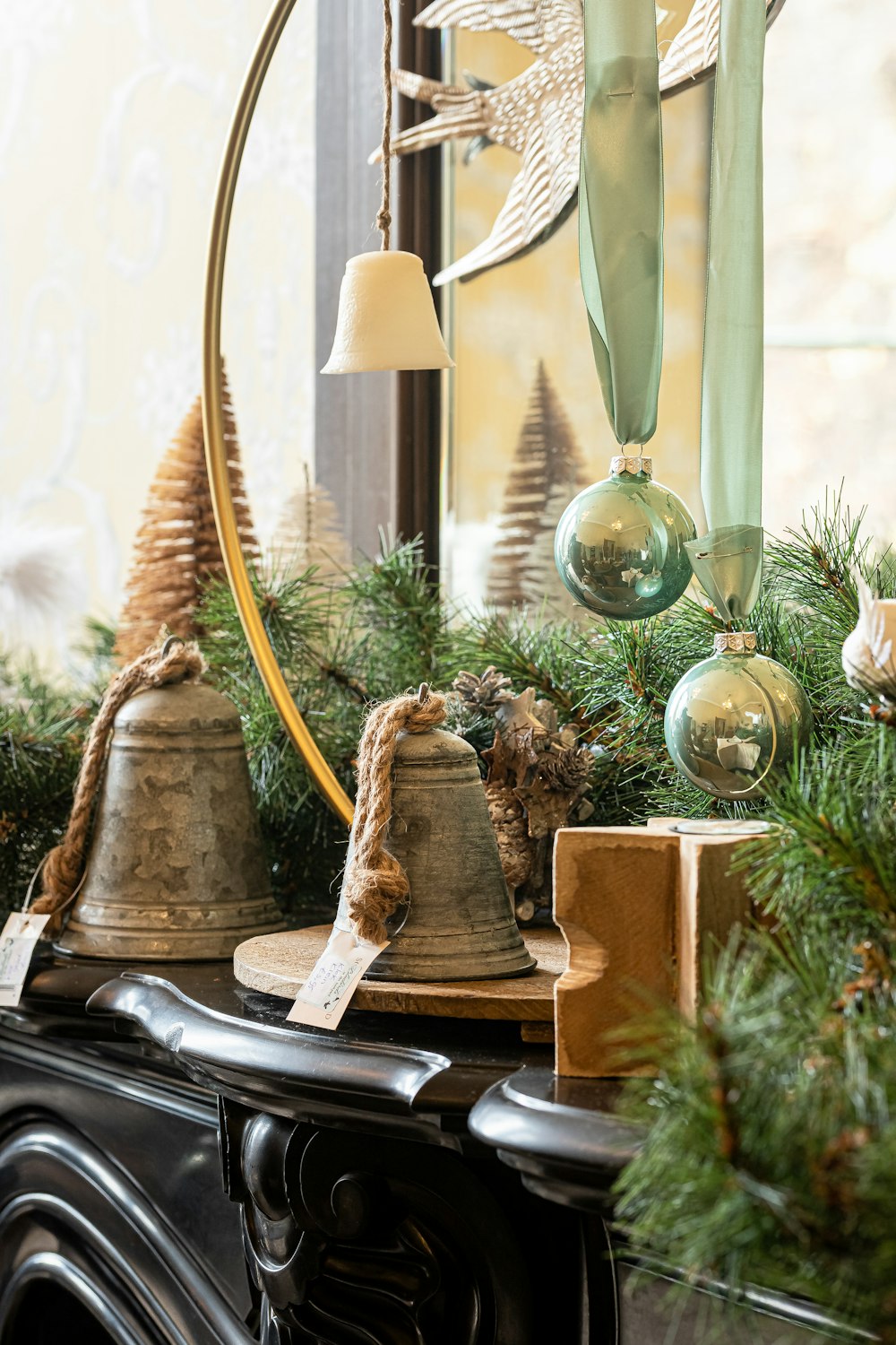 a christmas mantle with bells and evergreen branches