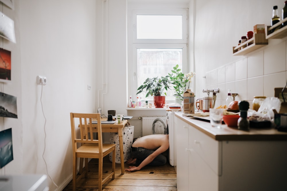 a person kneeling down in a kitchen next to a window