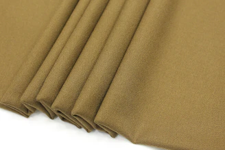 A pair of casual pants in muted olive green folded neatly on a rustic chair.