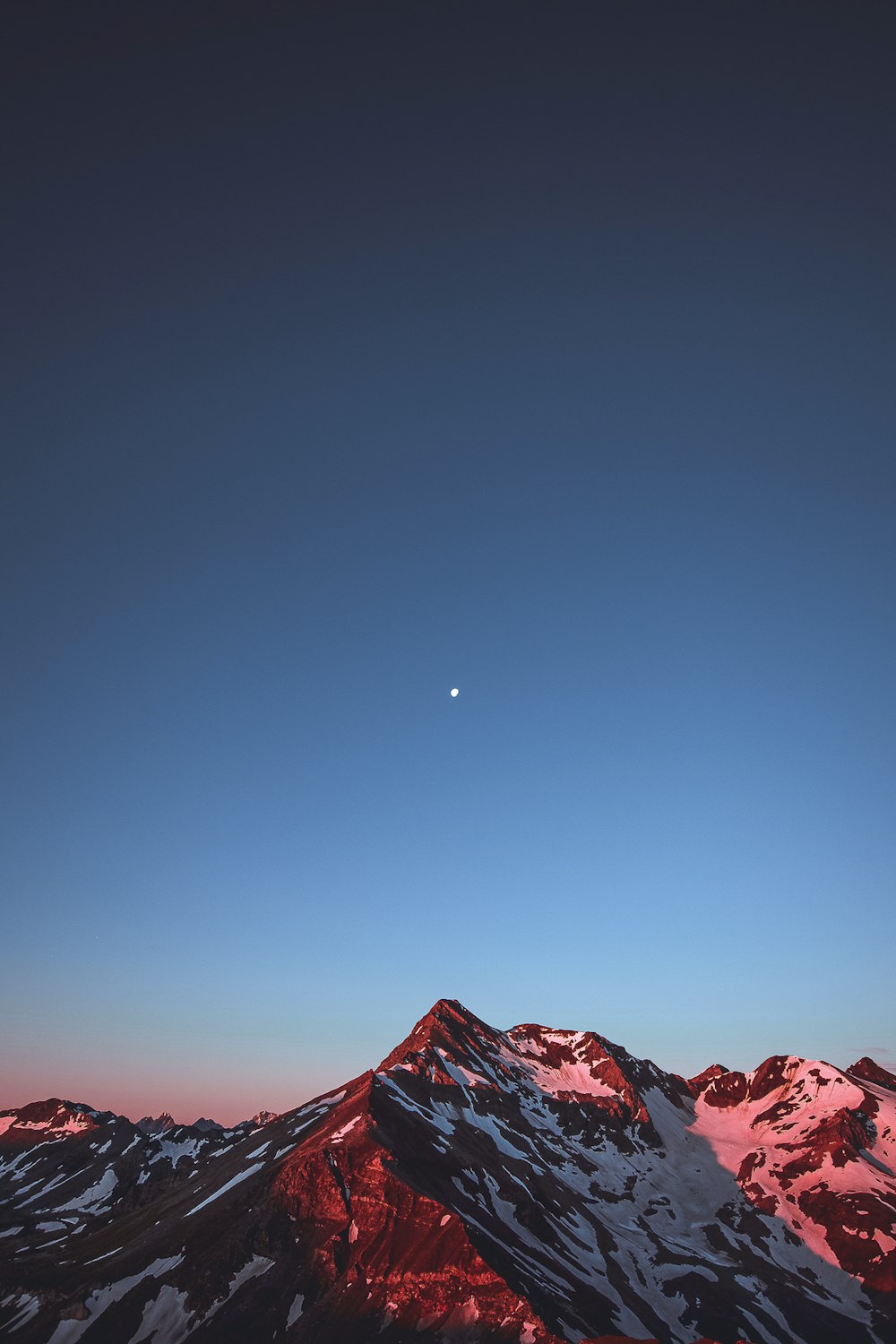 Una vista di una montagna con una luna nel cielo