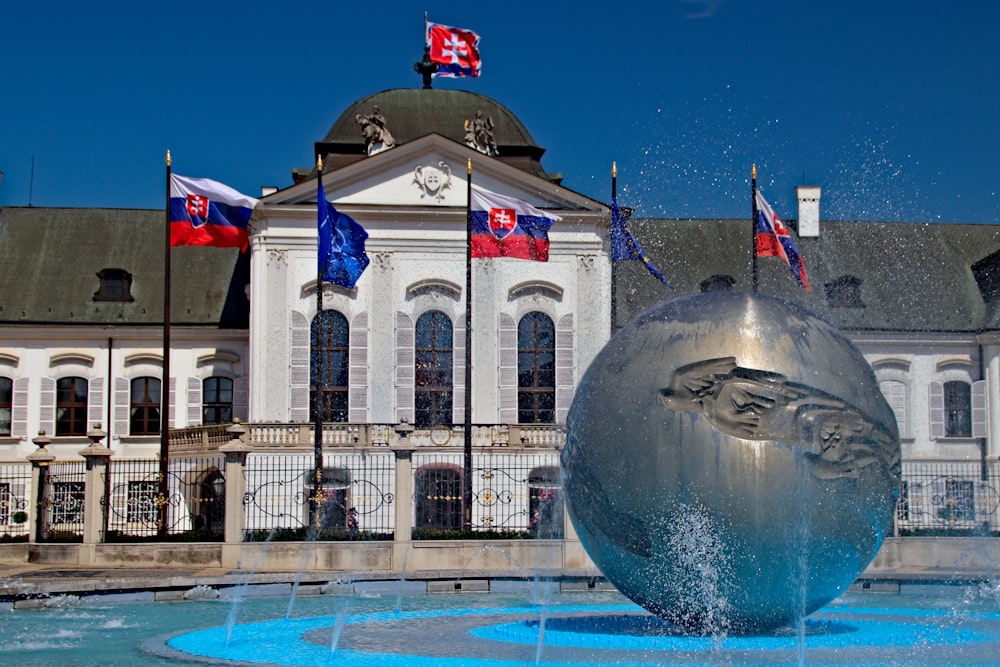 a fountain in front of a building with flags on it