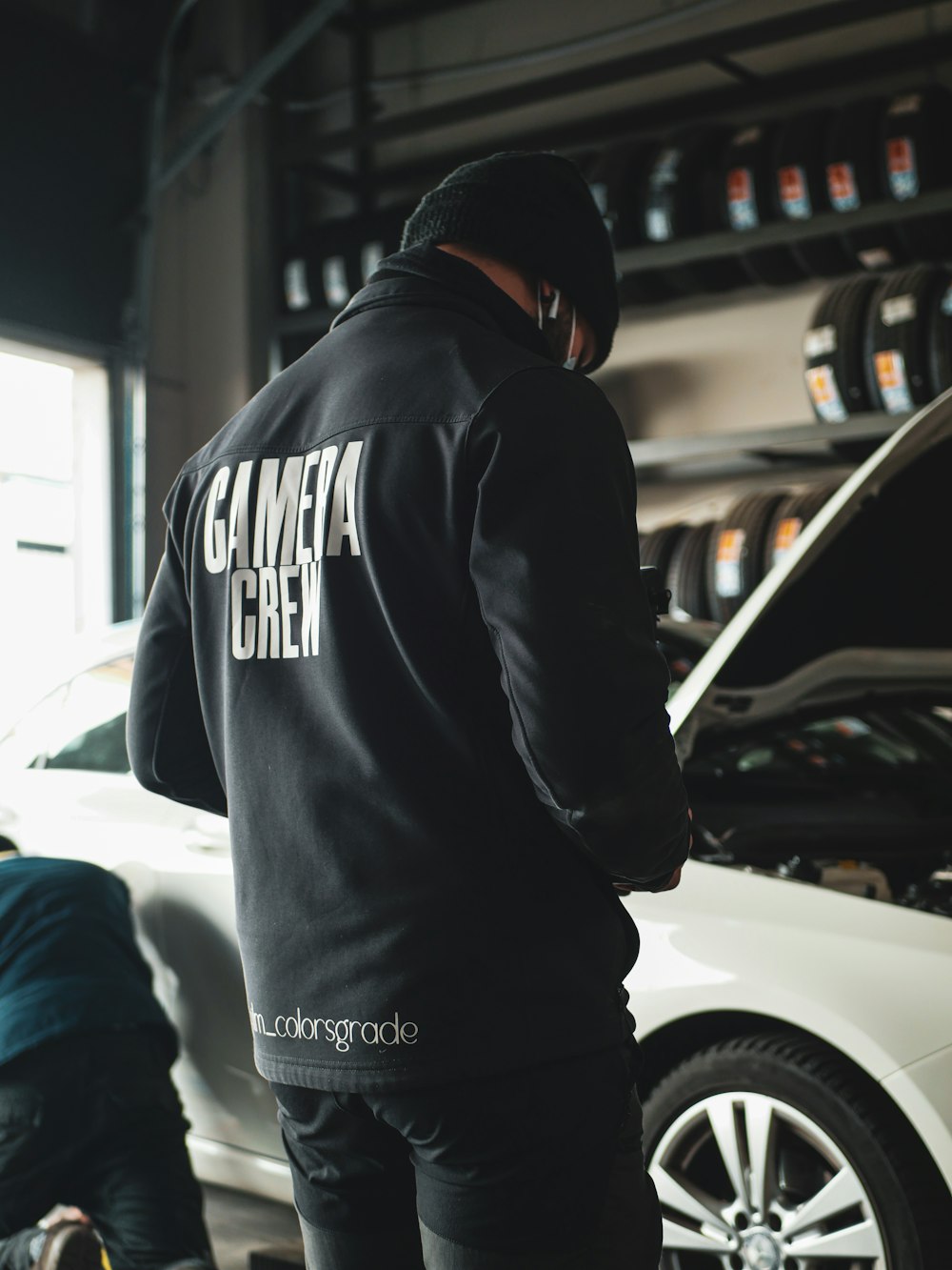 a man standing next to a car in a garage