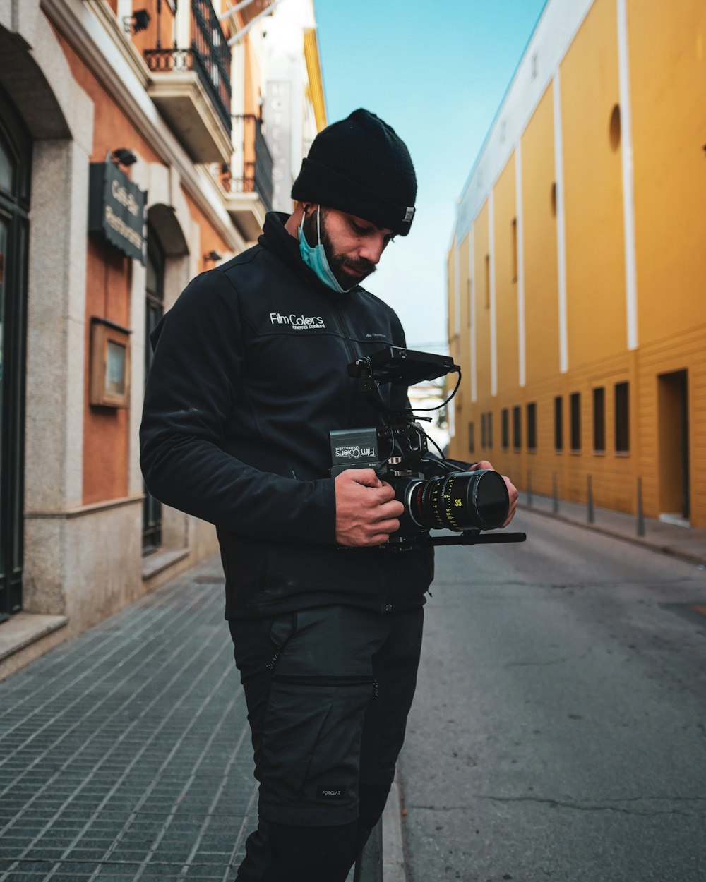 Un uomo in piedi su una strada con una macchina fotografica