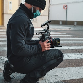 a man squatting down while holding a camera