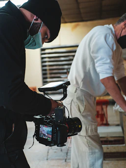 two men wearing masks and holding a camera