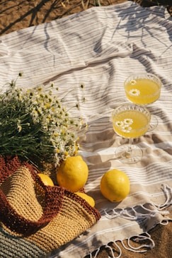two glasses of lemonade, a straw hat, and a straw bag on a