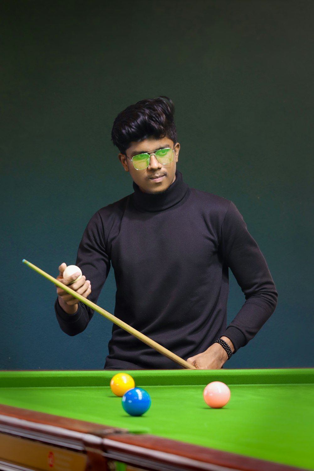 a man in a black shirt is playing pool