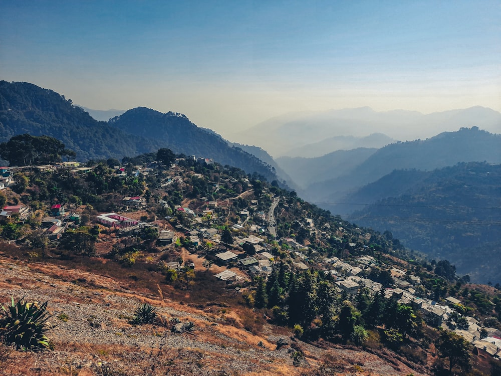 a view of a town on a hill with mountains in the background